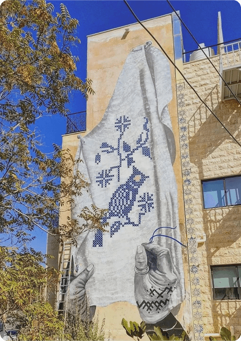 A limestone building with a blue bird mural in Jabal Al-Weibdeh